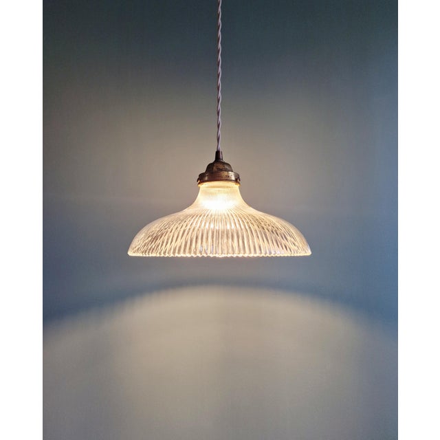 Holophane pendant light in clear fluted glass (27 cm diameter) with a brass bracket, 1930s. it has been rewired and is...