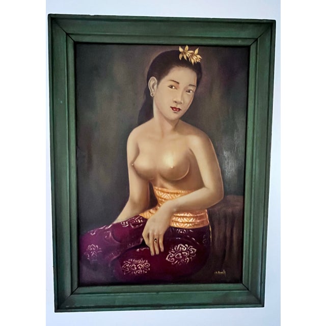 A captivating vintage oil on canvas portrait depicting a serene young Balinese woman seated in traditional attire....