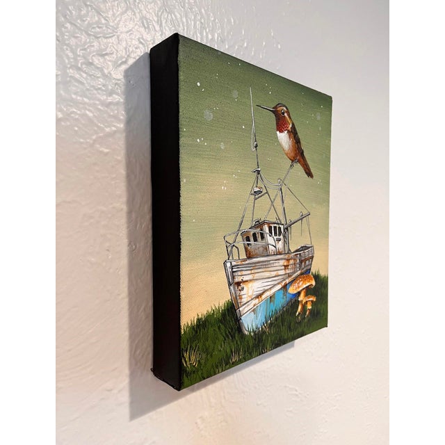 This artwork depicts a weathered fishing boat, partially submerged in lush green grass, with a vibrant hummingbird perched...