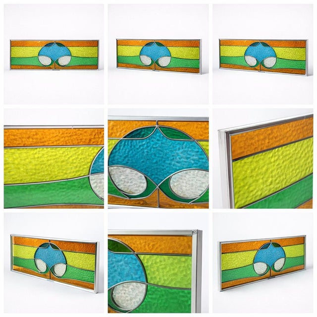 A striking vintage stained glass window panel featuring a bold mid-century geometric design in vibrant amber, green, and...