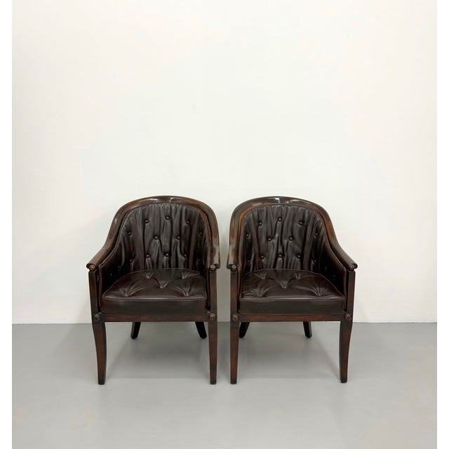 A sophisticated pair of Walter E. Smithe custom barrel armchairs featuring rich dark brown tufted leather upholstery...