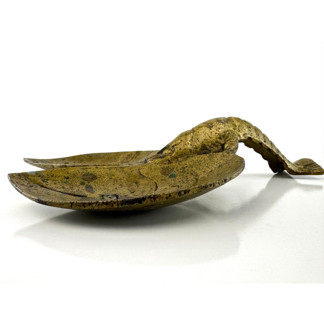 A sculptural vintage solid brass double dish featuring a figural lobster handle bridging two leaf-form bowls. The...