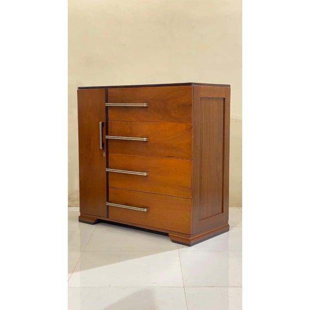 A stunningly handsome Mid-Century Modern chest of drawers or dresser cabinet made of solid teak with rosewood accents....