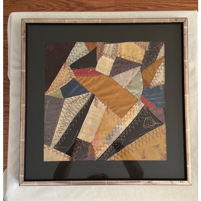 The image displays a framed abstract textile artwork known from the period of the 19th Century as "Crazy Quilt." Dark,...
