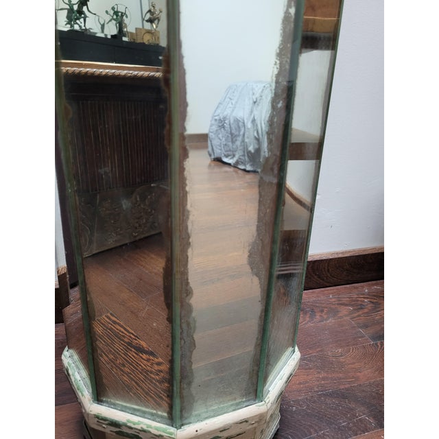 Hexagonal shaped stand made of mirrors, on all sides. The mirrors are on a wooden core, of which we can see the base Ideal...