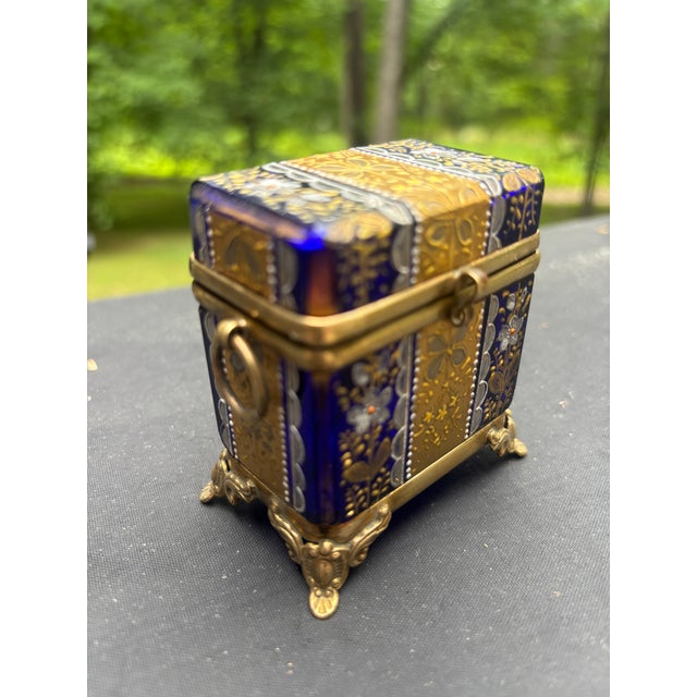 A miniature brass bound cobalt blue trinket box decorated all over in gilt and silver gilt and intricately-detailed...