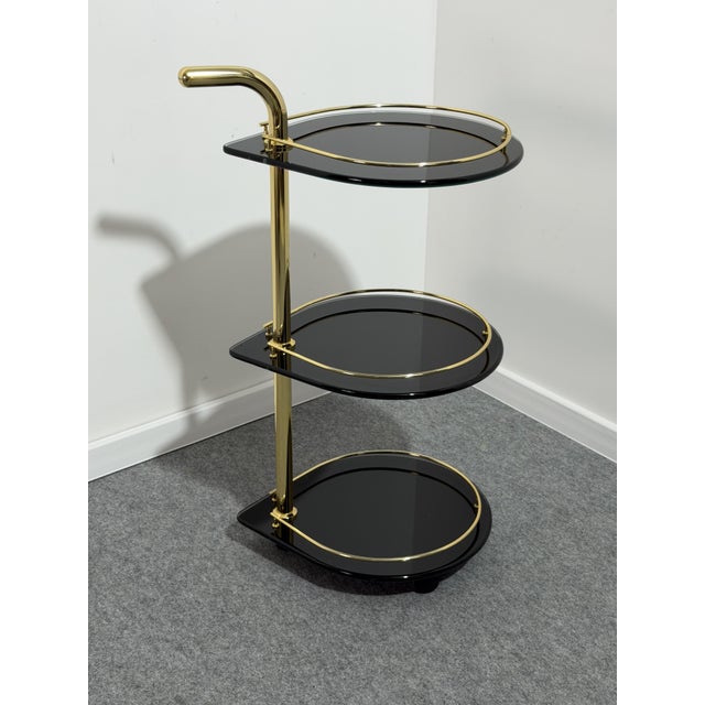 Rare three-tier bar cart in gilded metal and smoked glass, 1970 Swivel casters. Note the unique shape of the glass. Good...