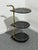 Rare three-tier bar cart in gilded metal and smoked glass, 1970 Swivel casters. Note the unique shape of the glass. Good...