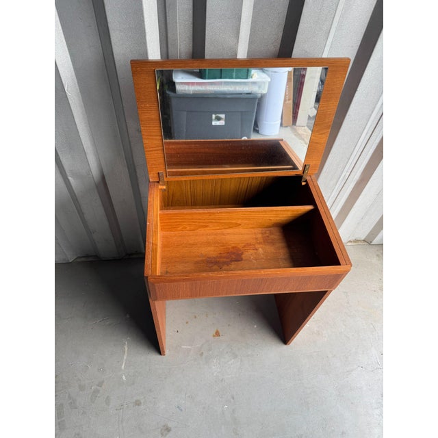 A Danish Modern teak vanity desk by EAEVA Co., marked "Made in Denmark 258" inside. The hinged top lifts to reveal a...