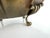 A vintage hammered brass bowl featuring a beautifully scalloped rim, ornate foliate side handles, and four sculptural claw...