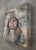 This artwork presents a close-up portrait of an older man, characterized by deep-set eyes and a warm, inviting smile. The...