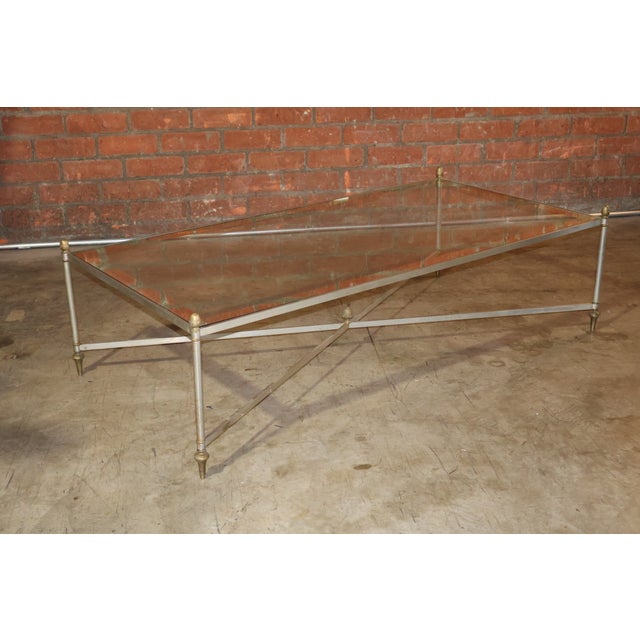 A fine vintage coffee table in steel and brass by Maison Jansen. Includes new glass top with mirrored edge detail. In...