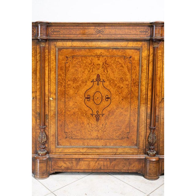 English Victorian sideboard in walnut burl with maple inlay inserts. The front is marked by a central door with a shelf...