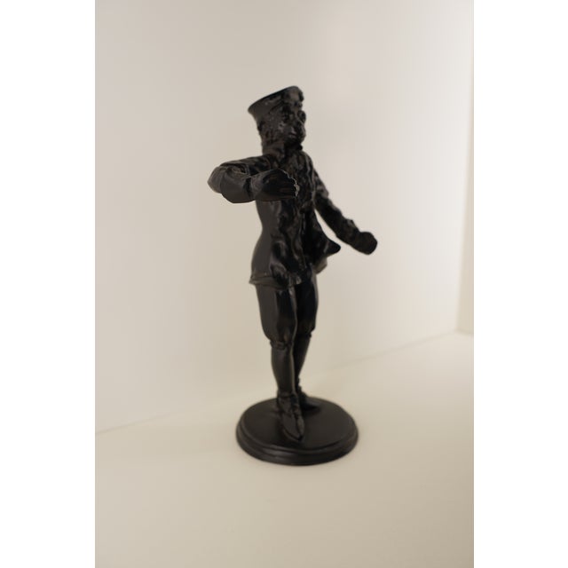 This vintage cast iron figurine depicts a Colonial-era gentleman dressed in period attire, including breeches, a long...