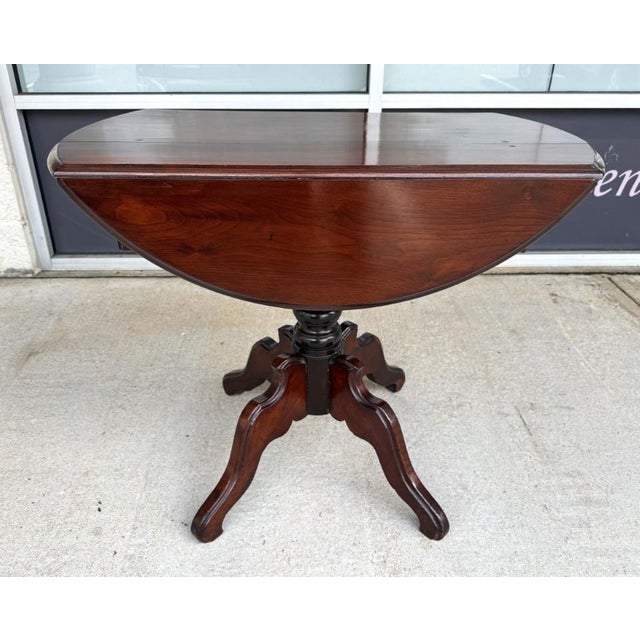 This antique mahogany drop-leaf table features a space-saving round top that opens to provide additional surface area when...