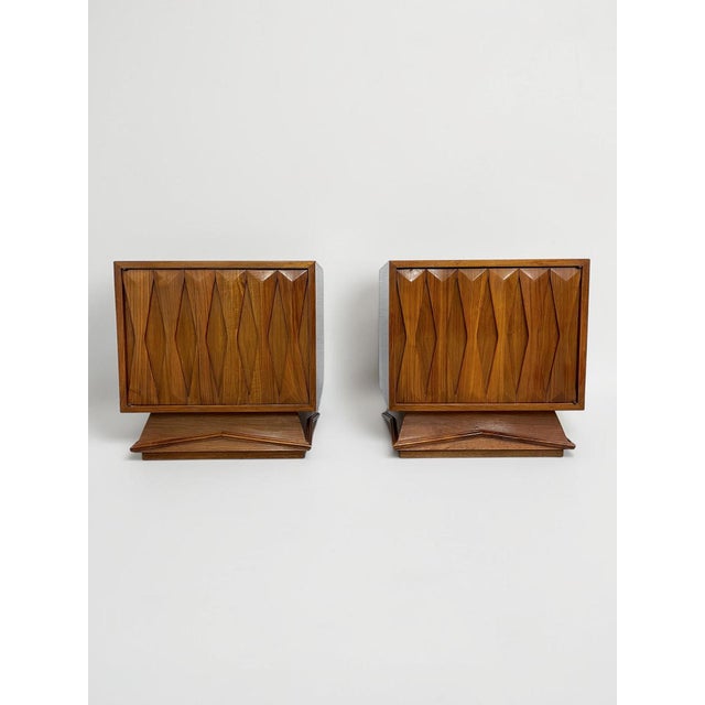 A striking matching pair of vintage 1960s MCM / Mid-Century Modern walnut nightstands, distinguished by dramatic...