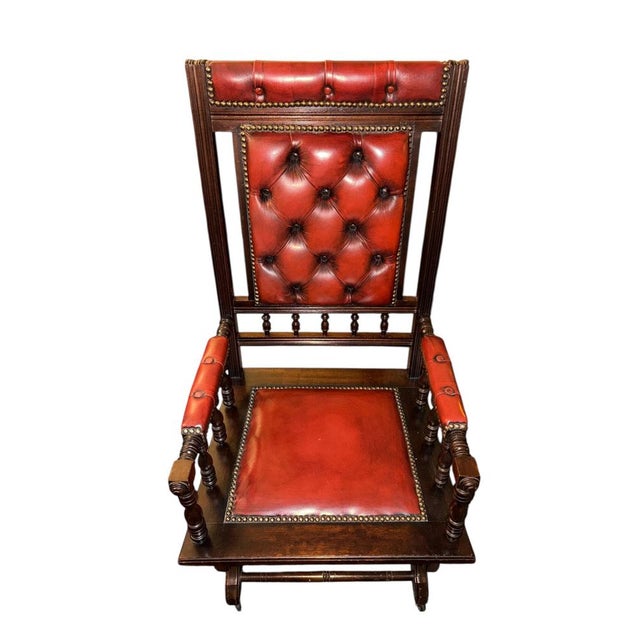 English platform rocking chair upholstered in deep button-tufted oxblood leather in the Chesterfield tradition. Solid...