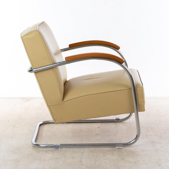 Chrome-plated steel tubing. Upholstered and covered in beige leather. Stained wooden armrests, hand-polished with shellac....