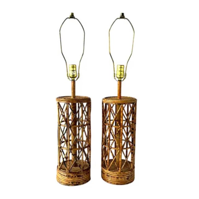 Vintage Pair of Mid Century Bamboo and Rattan Table Lamps. This pair of lamps showcase a cylindrical lattice design with a...