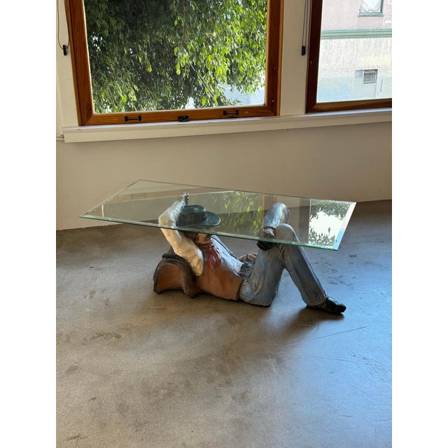 Sculptural “sleeping cowboy” coffee table with glass top. 1970s style. Bold form with a strong pop art/western influence....