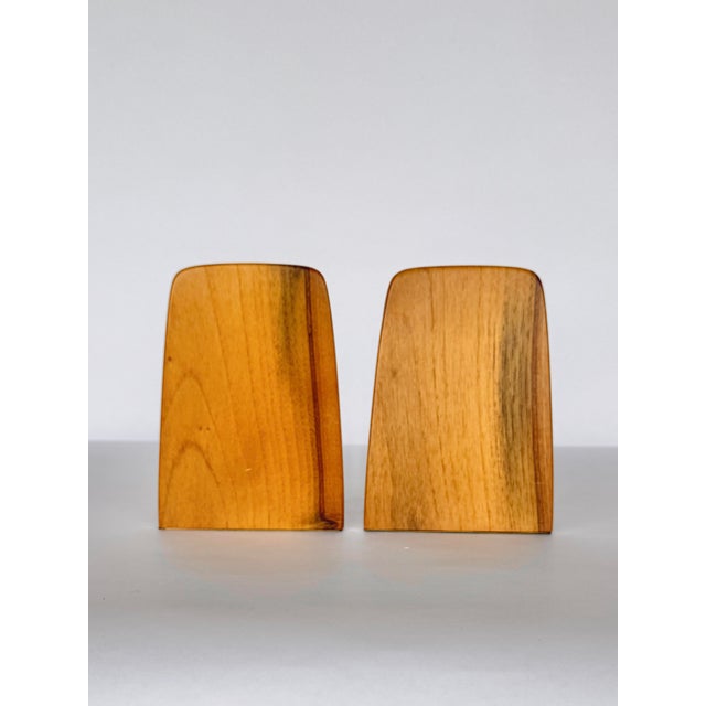 A pair of mid-century teak bookends with a strongly sculptural form. Simple and architectural in warm-toned lacquered teak...