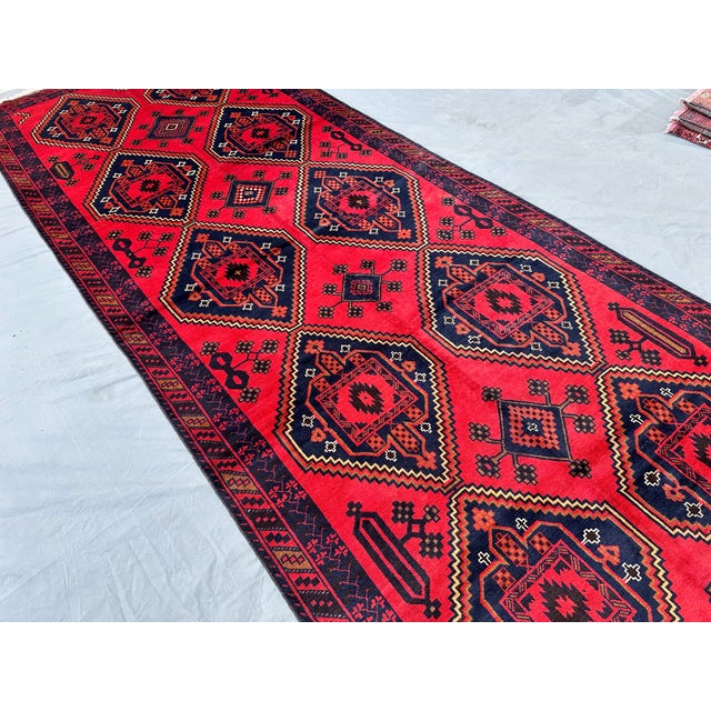This striking Baluch runner features paired stepped-diamond medallions in deep navy, each centered with a bold cruciform...