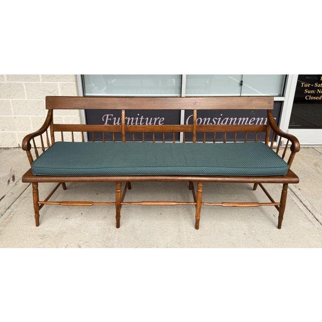 This antique spindle-back bench features gracefully turned spindles, gently scrolled arms, and a warm, timeworn wood...