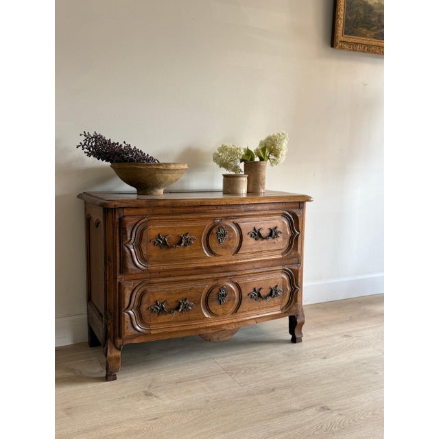 A 17th-century French walnut commode of two long drawers, the fronts worked in shaped, molded panels around central...