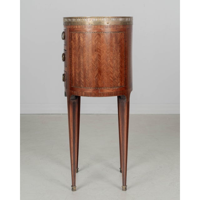 An early 20th century French Louis XVI style marquetry oval side table made of veneers of mahogany, walnut and tulipwood...