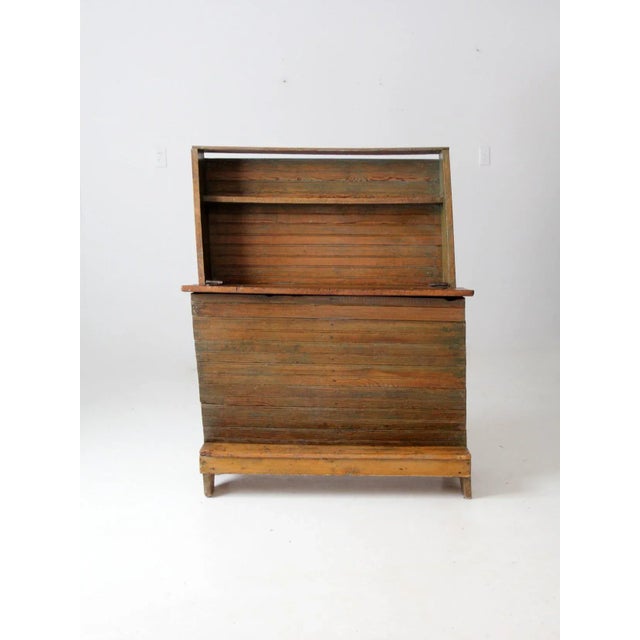An antique primitive storage chest featuring a rustic bead-board construction, large trunk-style storage compartment, and...