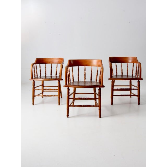 A set of three antique early 20th-century wood captain’s chairs with gently curved low backs, gracefully bentwood arms,...