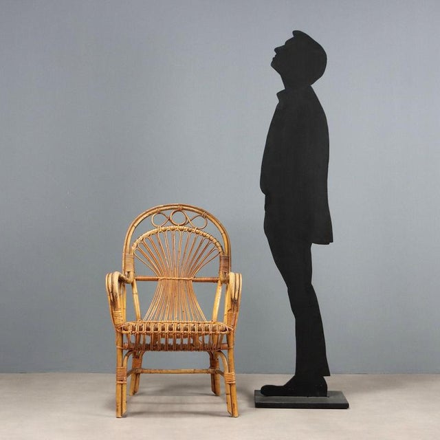 Vintage chair with armrests and high back made of bamboo This piece is attributed to the mentioned designer/maker. It has...