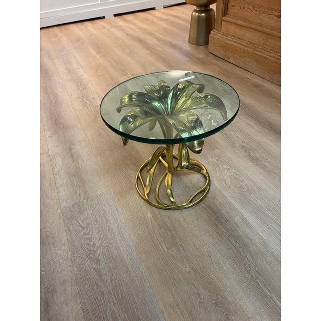 A striking example of 1960s Hollywood Regency design, this vintage side table features a sculptural gilded metal base...