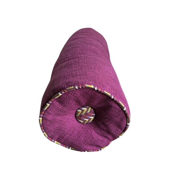 Elegant contemporary bolster pillow upholstered in a rich plum / magenta textured fabric with decorative contrast welt...