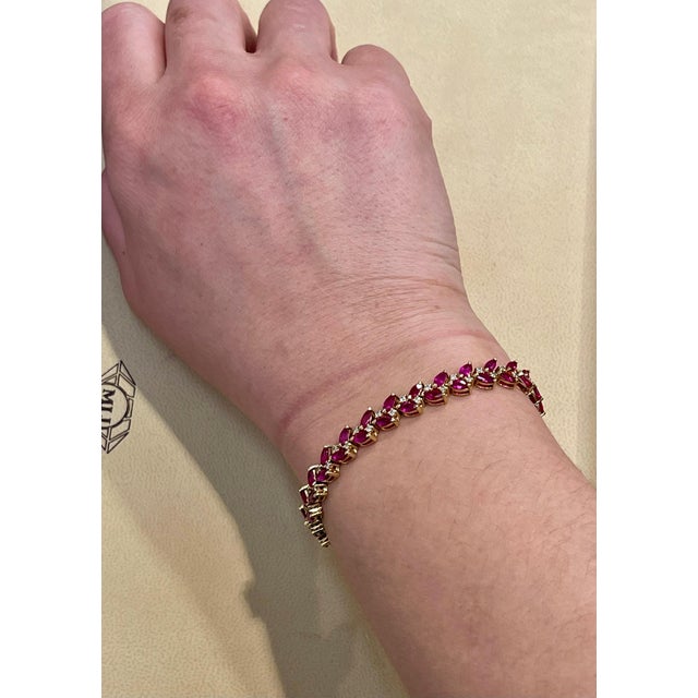 This bracelet boasts marquise-cut Rubies in 14k Yellow Gold. prong settings, beautifully complemented by glittering round-...