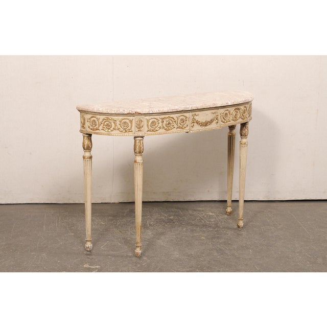 An Italian carved and painted wood console table, with marble top, from the mid 20th century. This vintage table from...