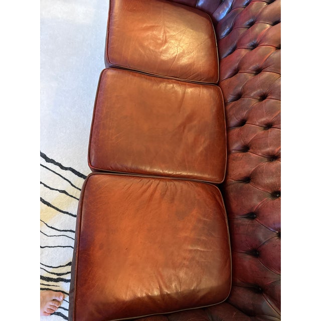 Classic three-seat Chesterfield (1979) in a rich oxblood leather with deep button tufting, rolled arms, and brass nailhead...