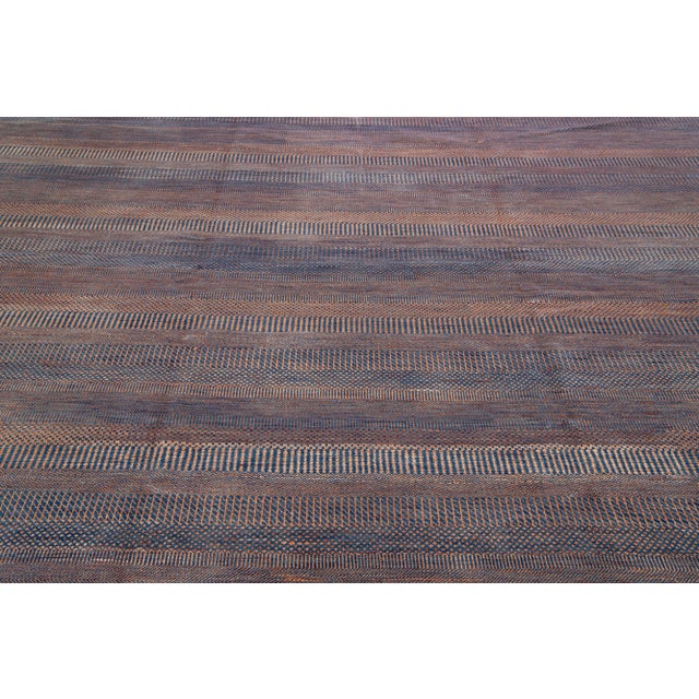 This elegant hand knotted rug is made of wool. It features a subtle orange and blue color scheme accented by an all-over...