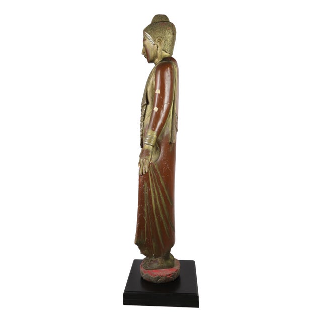 This Buddha statue is made of woodcarving, with gold foil and inlaid glass or semi-precious stones on the surface, showing...