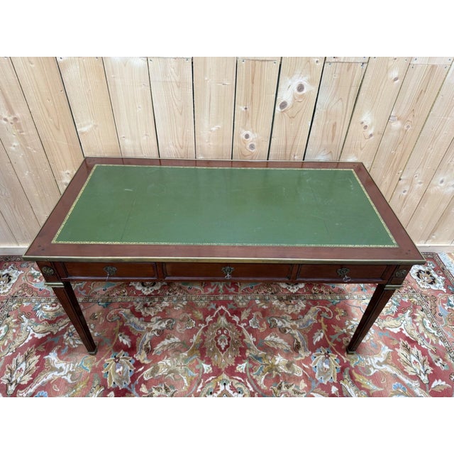A louis xvi style flat desk in solid mahogany. height under the frieze: 61 cm the rectangular top is encircled by a brass...