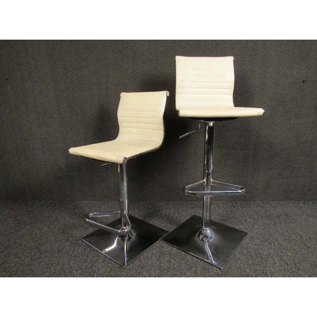 Sleek pair of vintage modern bar stools with adjustable seats. Finished in a white automotive-style vinyl upholstery with...