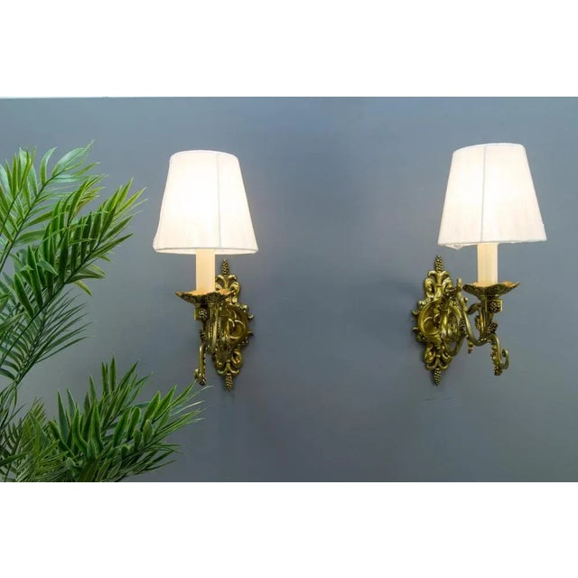 A beautiful pair of French Louis XVI-style wall lights. Made of bronze in the shape of large scrolls and decorated with...