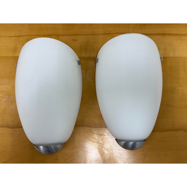 Design Plus Gallery presents a Pair of Santir Opaline Glass Wall Sconces by Ikea. Each sconce has a softly curved opaline...