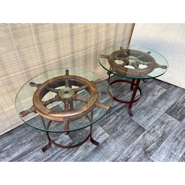 A pair of Vintage Handcrafted Ship's Wheel Glass Top Side Tables. Circa 1970s Features an authentic teak ship's wheel with...