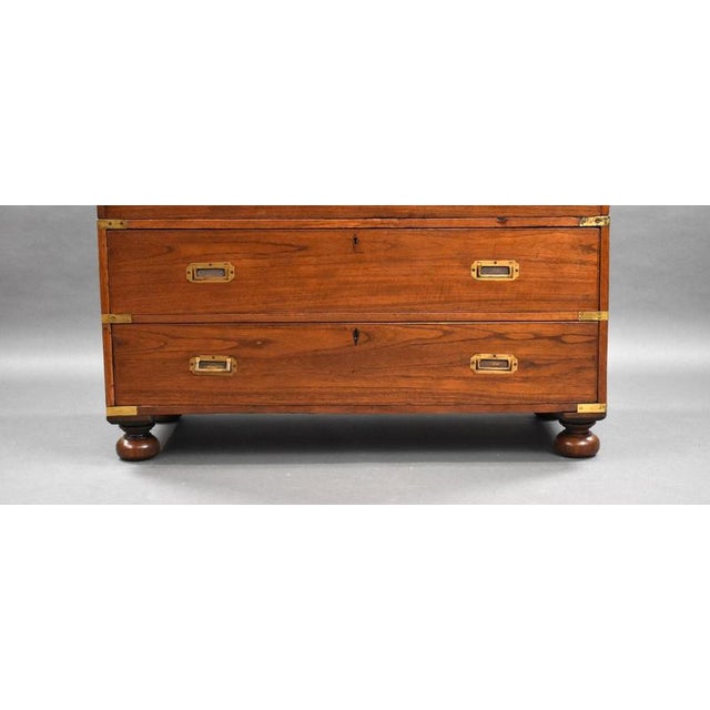 For sale is a good quality Victorian teak campaign secretaire chest, the top drawer with a fall front opening to a fitted...