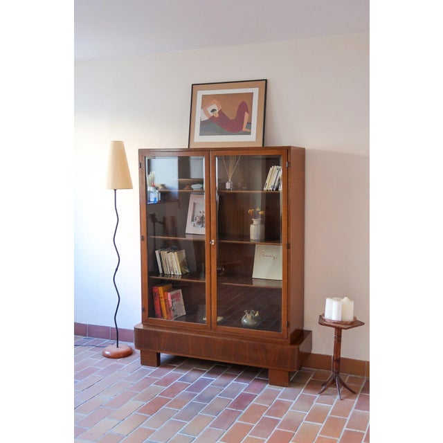 Walnut glazed bookcase, 1960s, Art Deco in spirit. Two glazed doors in timber frames that lock with the original lock, and...
