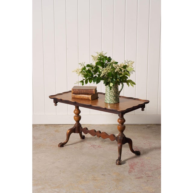 Antique English coffee table with a scalloped top, carved apron, and carved claw feet. A generous surface and classic...