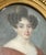 An elegant early 19th century portrait miniature depicting a young woman with softly curled coiffure and a rich russet...