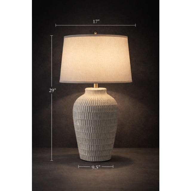 A sculptural 29” ribbed ceramic table lamp with a limestone-inspired finish and warm neutral tone. Featuring a deeply...
