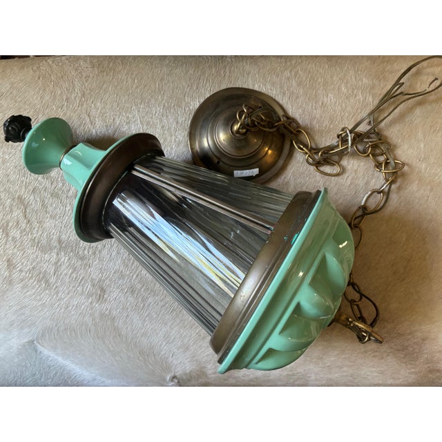 This is a pendant light fixture made of unlaquered brass and turquiose painted metal. The thick, polycarbonate panes are...